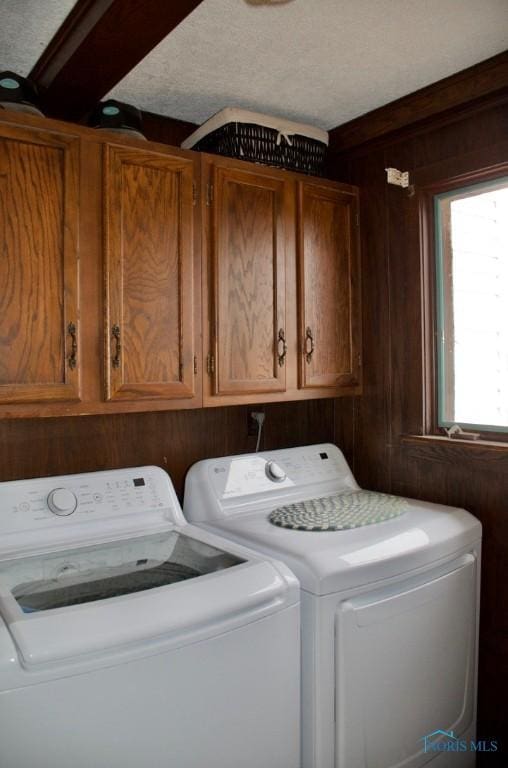 washroom with cabinets, washer and clothes dryer, and wood walls