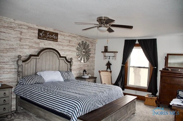 bedroom featuring ceiling fan, wooden walls, carpet floors, and a textured ceiling