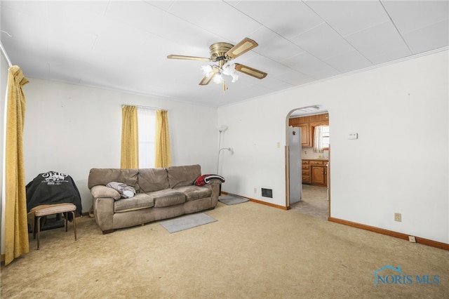 living room with a healthy amount of sunlight, ceiling fan, light colored carpet, and ornamental molding