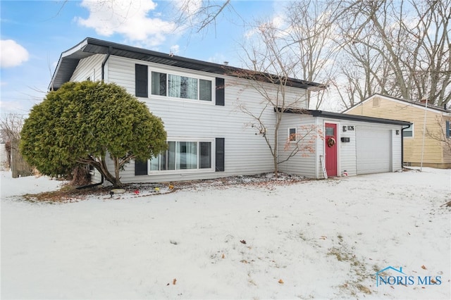 snow covered back of property featuring a garage