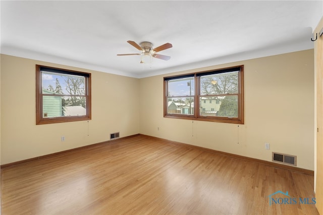 spare room with ceiling fan, a wealth of natural light, and light hardwood / wood-style flooring