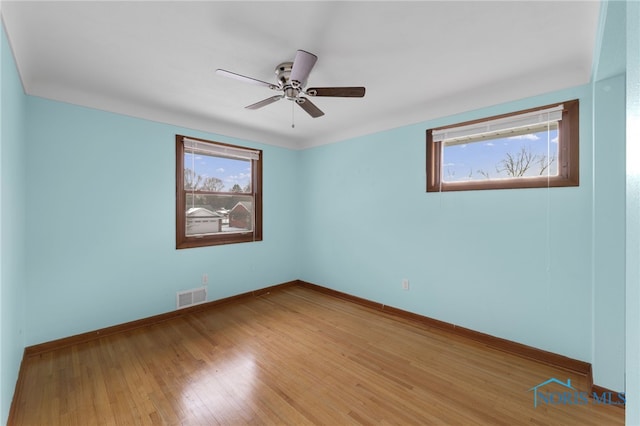 empty room with wood-type flooring, a wealth of natural light, and ceiling fan