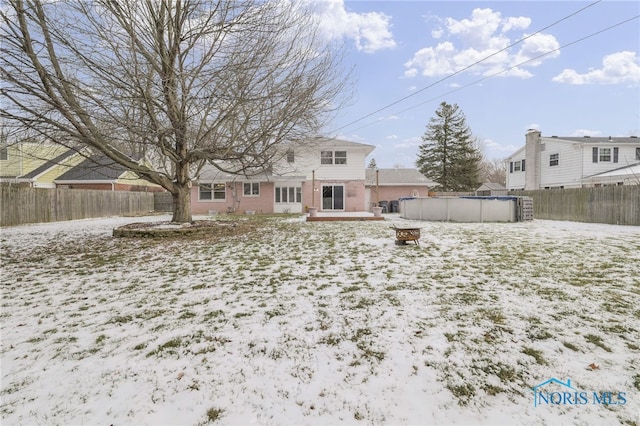 snow covered house featuring a fenced in pool