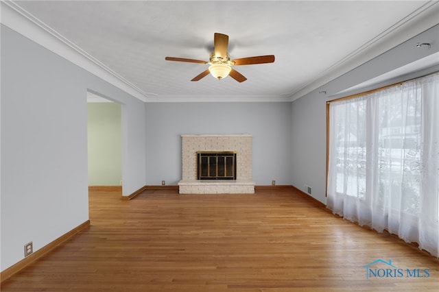 unfurnished living room with crown molding, a fireplace, ceiling fan, and light wood-type flooring