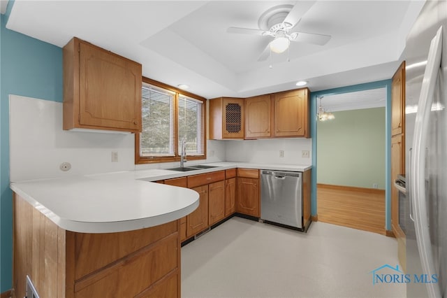 kitchen with ceiling fan with notable chandelier, sink, appliances with stainless steel finishes, a tray ceiling, and kitchen peninsula