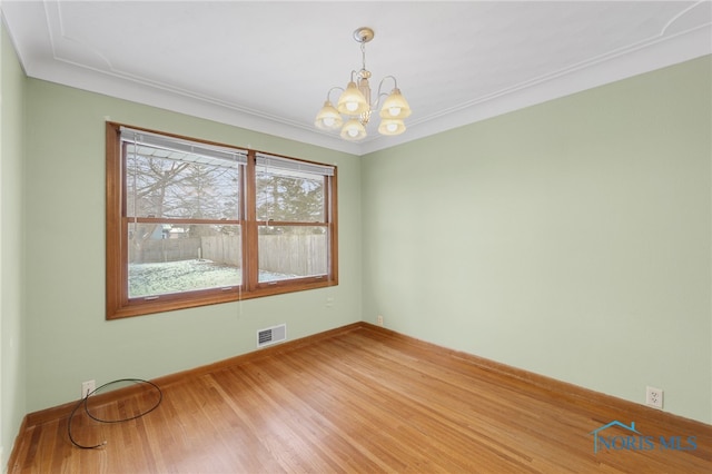 unfurnished room with hardwood / wood-style flooring, a notable chandelier, and ornamental molding