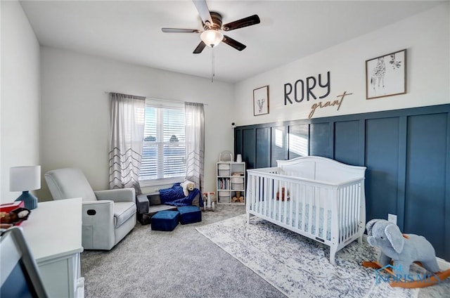 bedroom with carpet, a nursery area, and ceiling fan