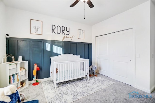 carpeted bedroom featuring ceiling fan, a closet, and a nursery area