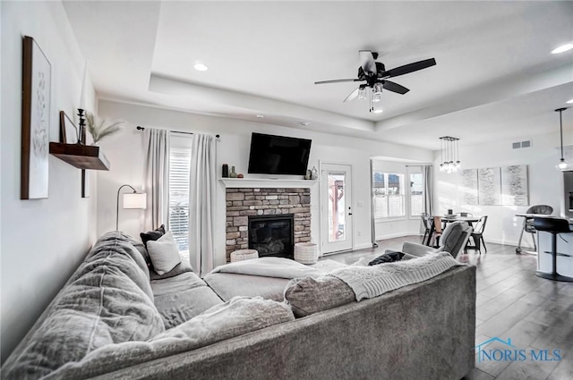 living room featuring a raised ceiling, ceiling fan, a fireplace, and hardwood / wood-style flooring