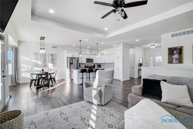 living room featuring a tray ceiling, ceiling fan, and hardwood / wood-style floors