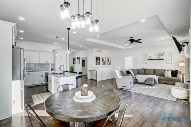 dining room featuring a tray ceiling, ceiling fan, hardwood / wood-style flooring, and sink