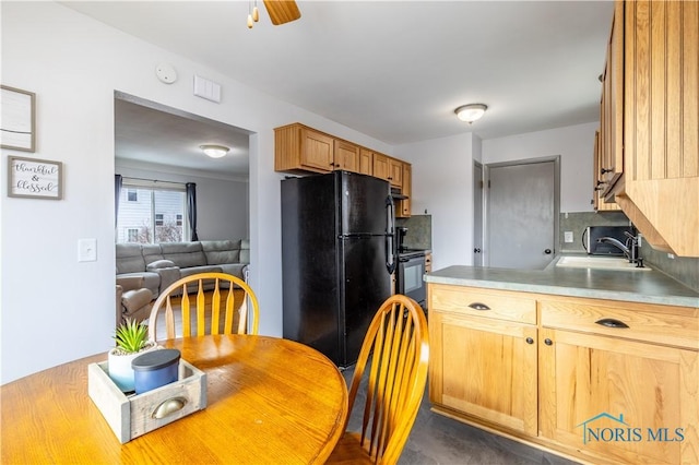 kitchen featuring ceiling fan, black refrigerator, range, and sink