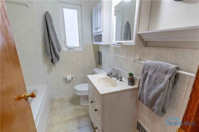 bathroom with tile patterned floors, vanity, toilet, and tile walls