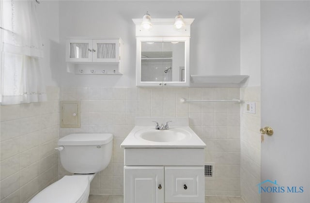 bathroom with vanity, toilet, and tile walls