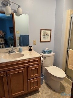 bathroom featuring vanity, toilet, and a shower with door