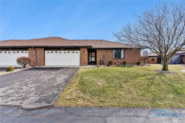 ranch-style home featuring a garage, aphalt driveway, roof with shingles, a front lawn, and brick siding