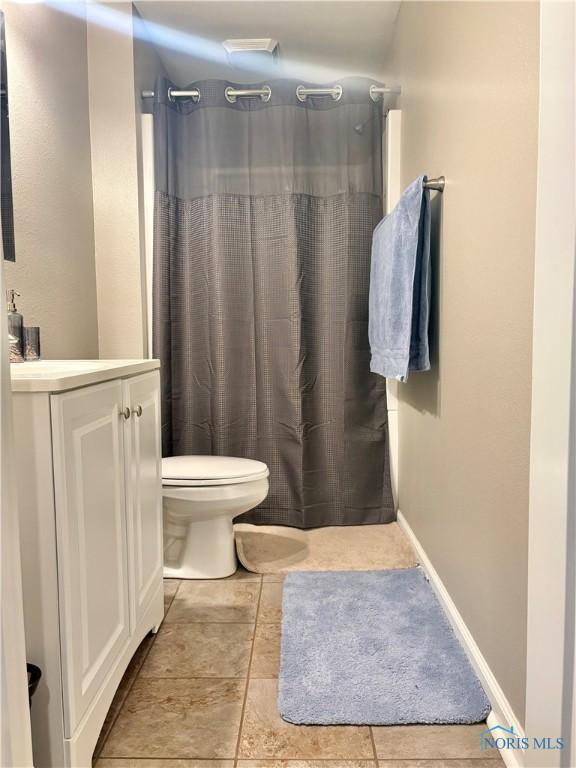 bathroom with curtained shower, toilet, vanity, and tile patterned flooring