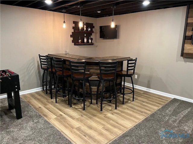 bar with pendant lighting and hardwood / wood-style flooring