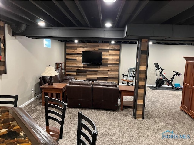 carpeted living room featuring wood walls