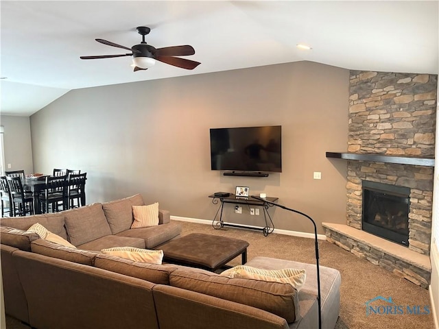 carpeted living room featuring ceiling fan, vaulted ceiling, and a stone fireplace