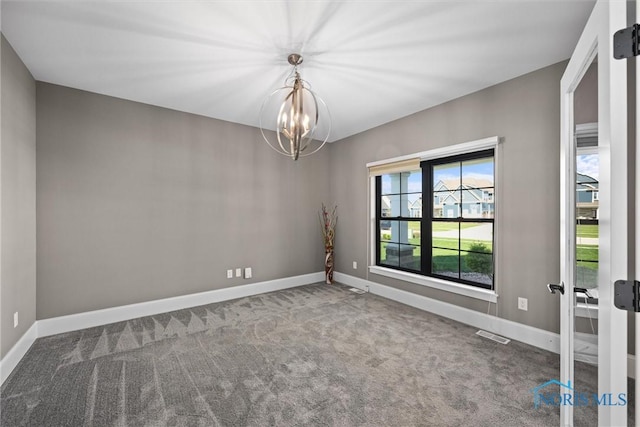 spare room featuring an inviting chandelier and carpet flooring