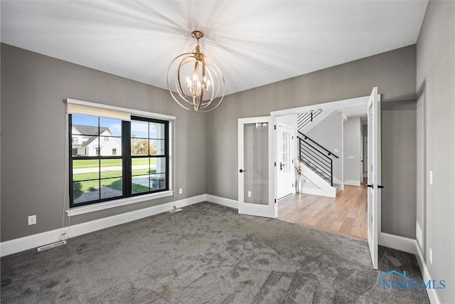 empty room with french doors, a chandelier, and carpet