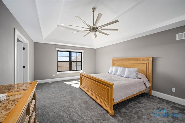 bedroom with dark carpet, ceiling fan, and a tray ceiling