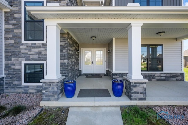 view of exterior entry with covered porch and french doors