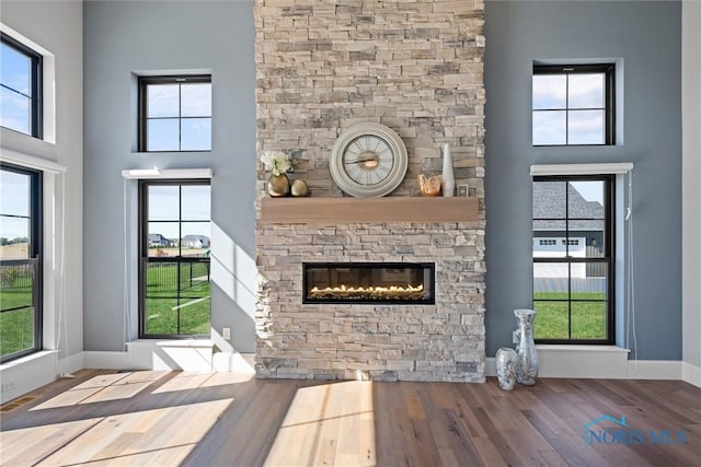 unfurnished living room featuring a high ceiling, a fireplace, and hardwood / wood-style flooring