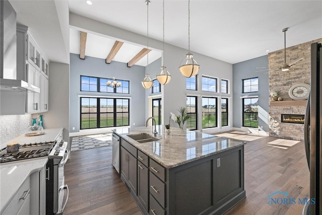 kitchen featuring sink, white cabinetry, a center island with sink, wall chimney range hood, and appliances with stainless steel finishes