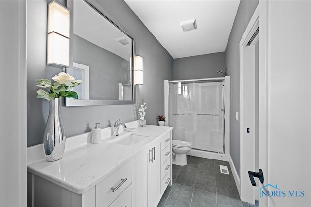 bathroom with toilet, vanity, tile patterned flooring, and a shower with shower door