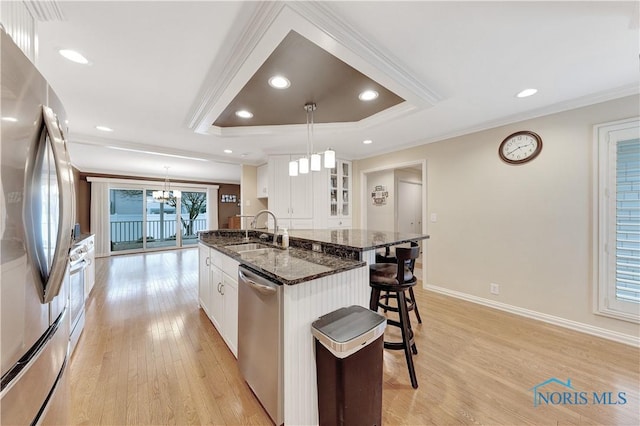 kitchen with sink, white cabinetry, dark stone countertops, pendant lighting, and stainless steel appliances