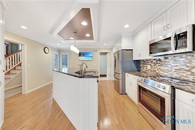 kitchen featuring decorative light fixtures, stainless steel appliances, a raised ceiling, and white cabinets