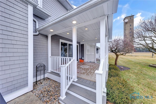 view of exterior entry featuring a lawn and a porch