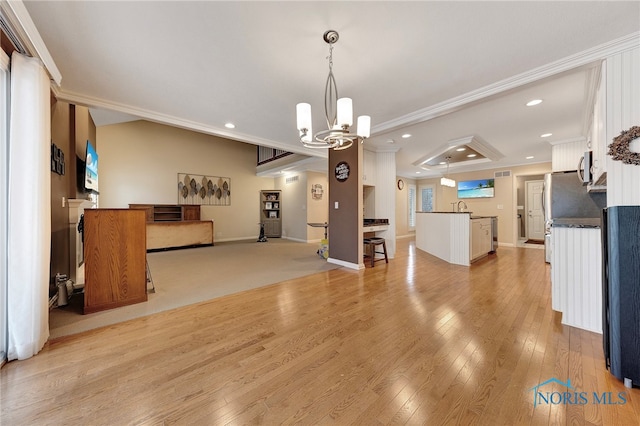 unfurnished dining area with an inviting chandelier, sink, ornamental molding, and light hardwood / wood-style floors