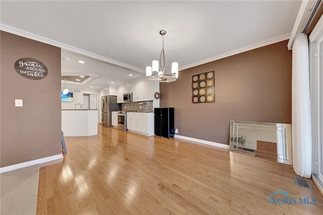 unfurnished living room with an inviting chandelier, ornamental molding, sink, and light hardwood / wood-style floors