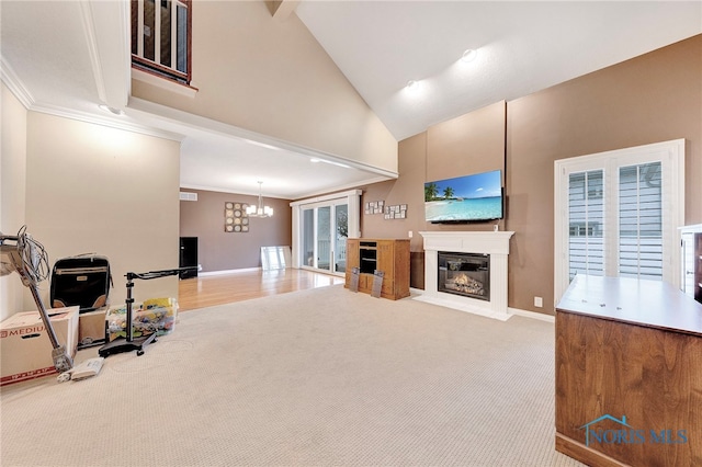 carpeted living room with ornamental molding, a notable chandelier, and high vaulted ceiling