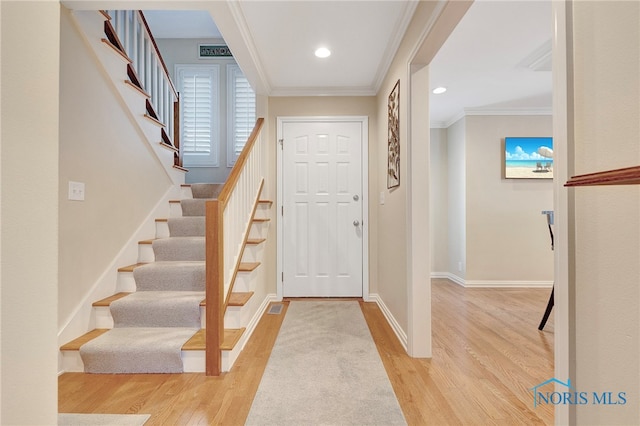 entryway with ornamental molding and light wood-type flooring