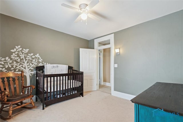 bedroom with a crib, ceiling fan, and carpet