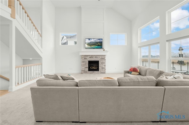 carpeted living room featuring a towering ceiling and a fireplace