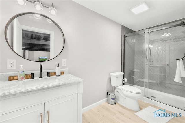 bathroom featuring a shower with shower door, hardwood / wood-style floors, toilet, and vanity