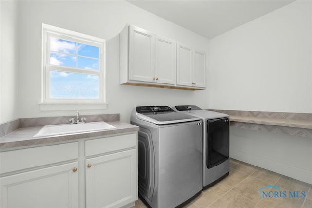 clothes washing area with cabinets, sink, and washing machine and clothes dryer