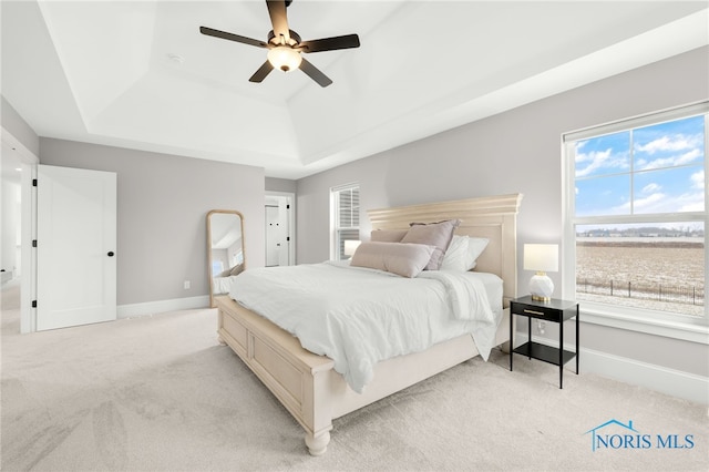 bedroom featuring light carpet, ceiling fan, and a raised ceiling