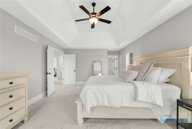 carpeted bedroom featuring ceiling fan and a raised ceiling