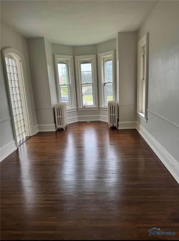 spare room featuring dark hardwood / wood-style flooring and radiator heating unit