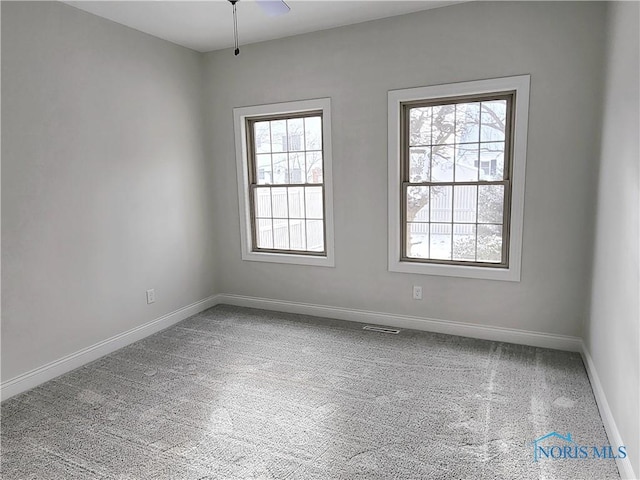 carpeted spare room featuring ceiling fan and a wealth of natural light