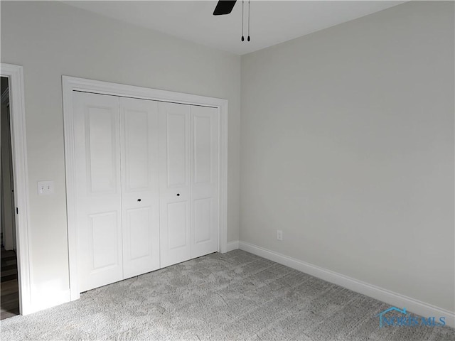 unfurnished bedroom featuring light carpet, ceiling fan, and a closet