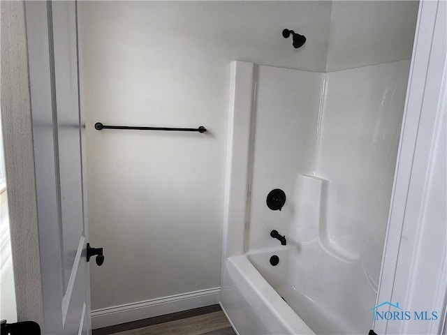 bathroom with hardwood / wood-style floors and washtub / shower combination