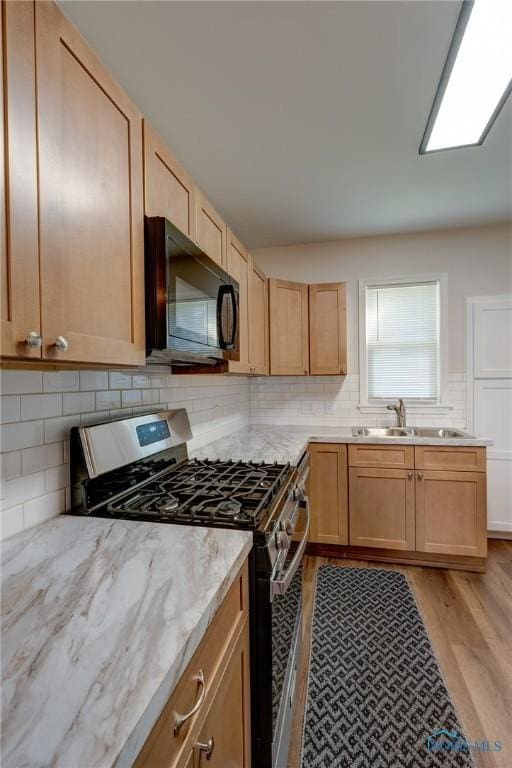 kitchen featuring sink, light hardwood / wood-style flooring, stainless steel gas stove, and light brown cabinets