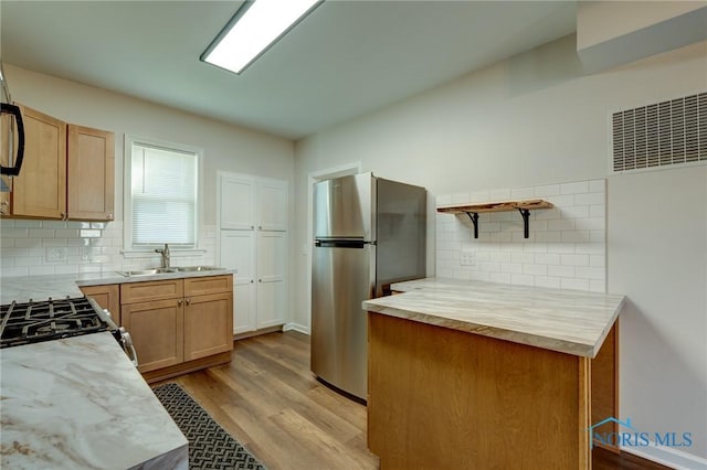 kitchen featuring stainless steel appliances, light hardwood / wood-style floors, decorative backsplash, and sink